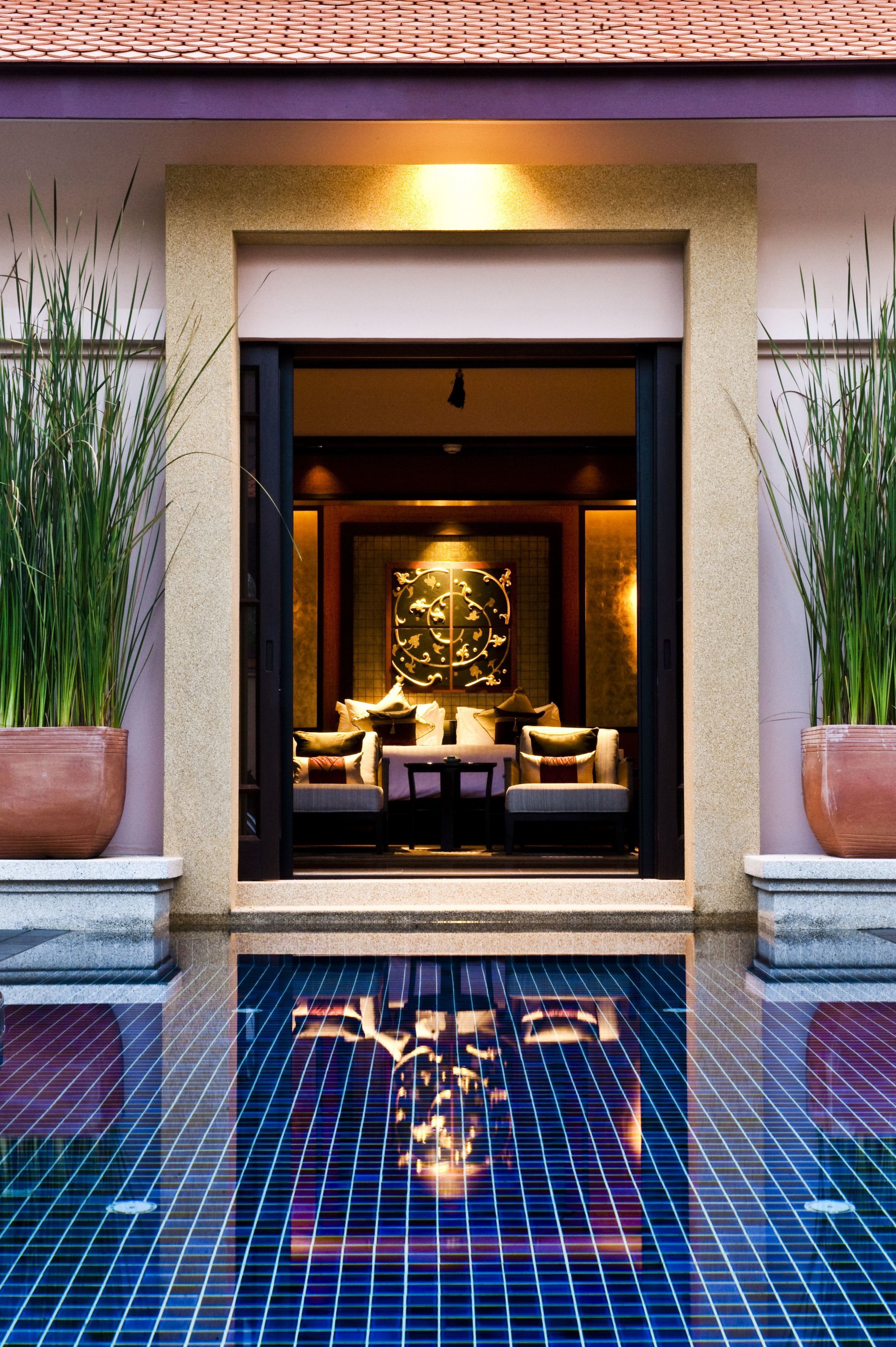 Una entrada de hotel con área de descanso, un amplio muro decorativo y plantas en macetas.
