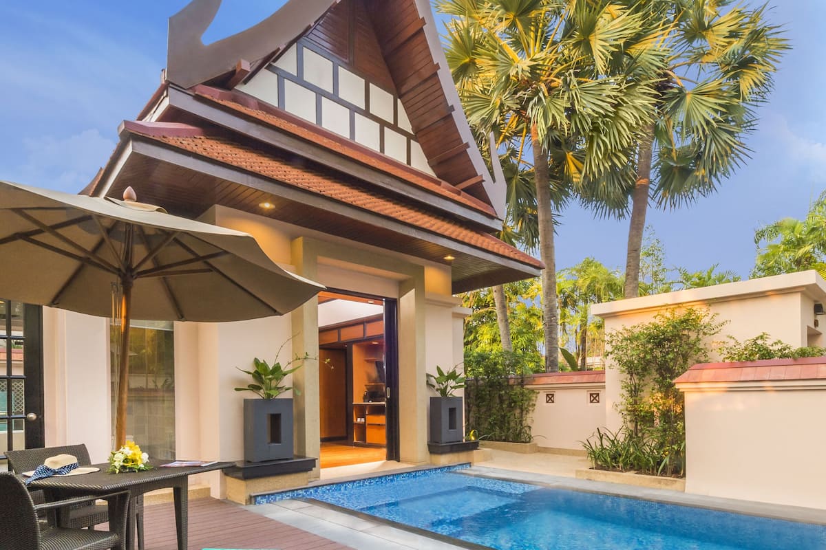 A poolside area with lounge chairs, a table, and a covered seating area.
