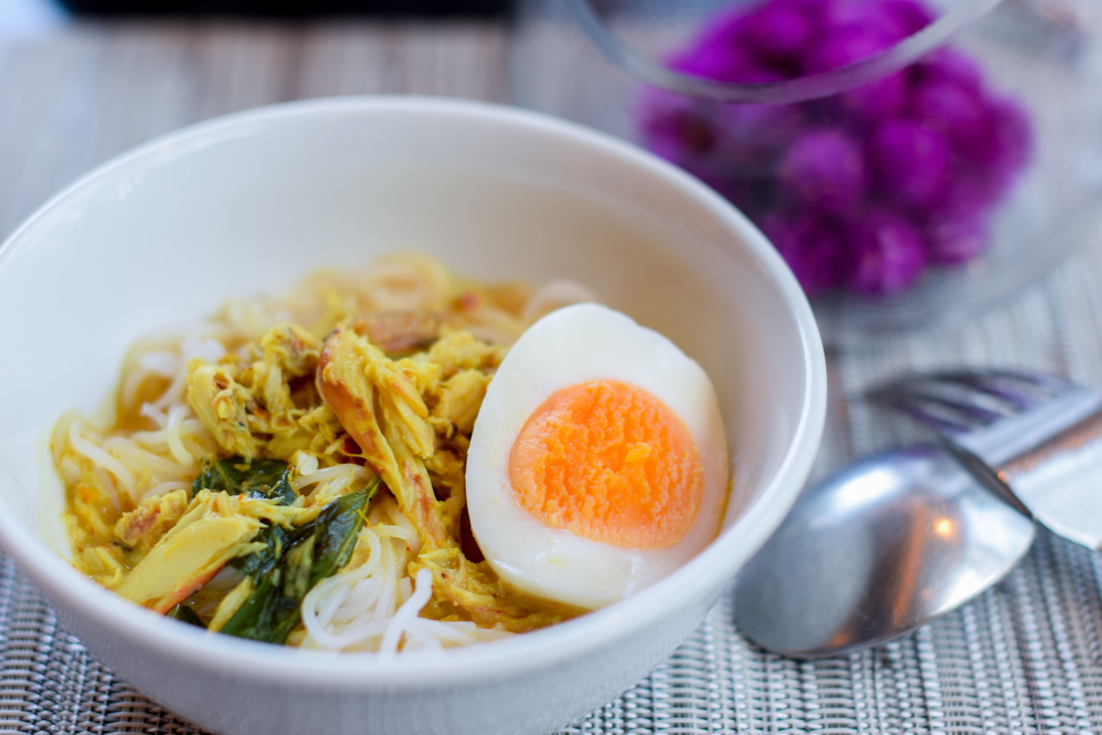 A bowl of noodle soup with a boiled egg and vegetables.