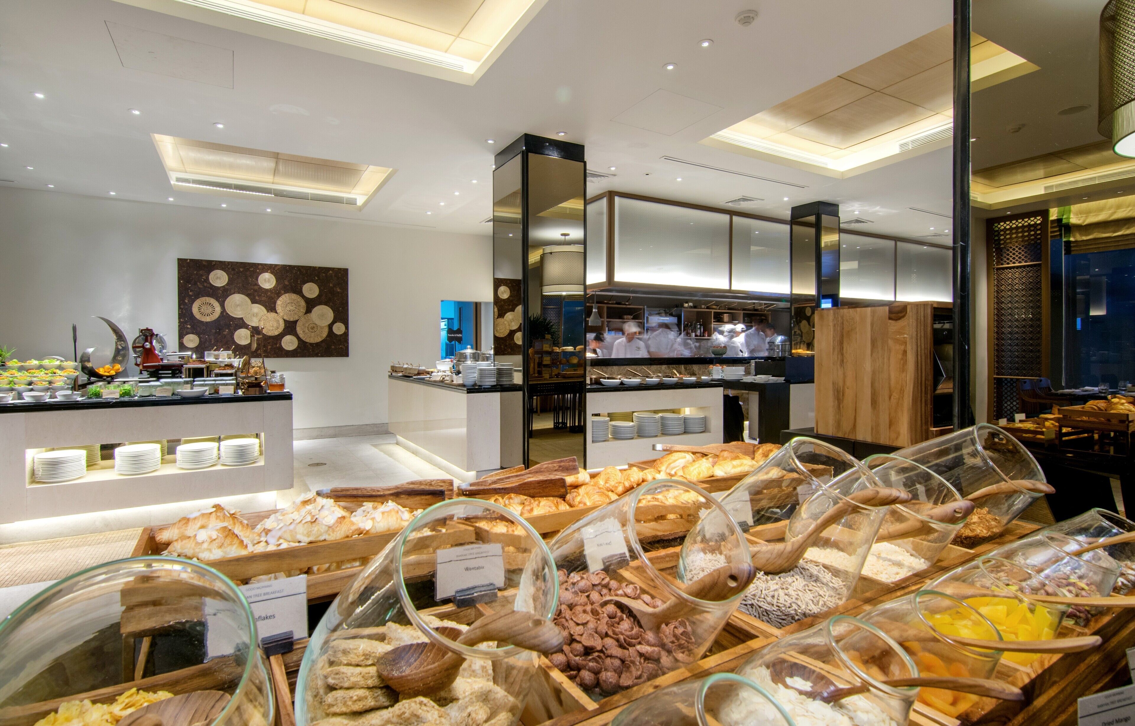 Un espace buffet où diverses préparations culinaires sont présentées dans des récipients en verre et sur des plateaux en bois.