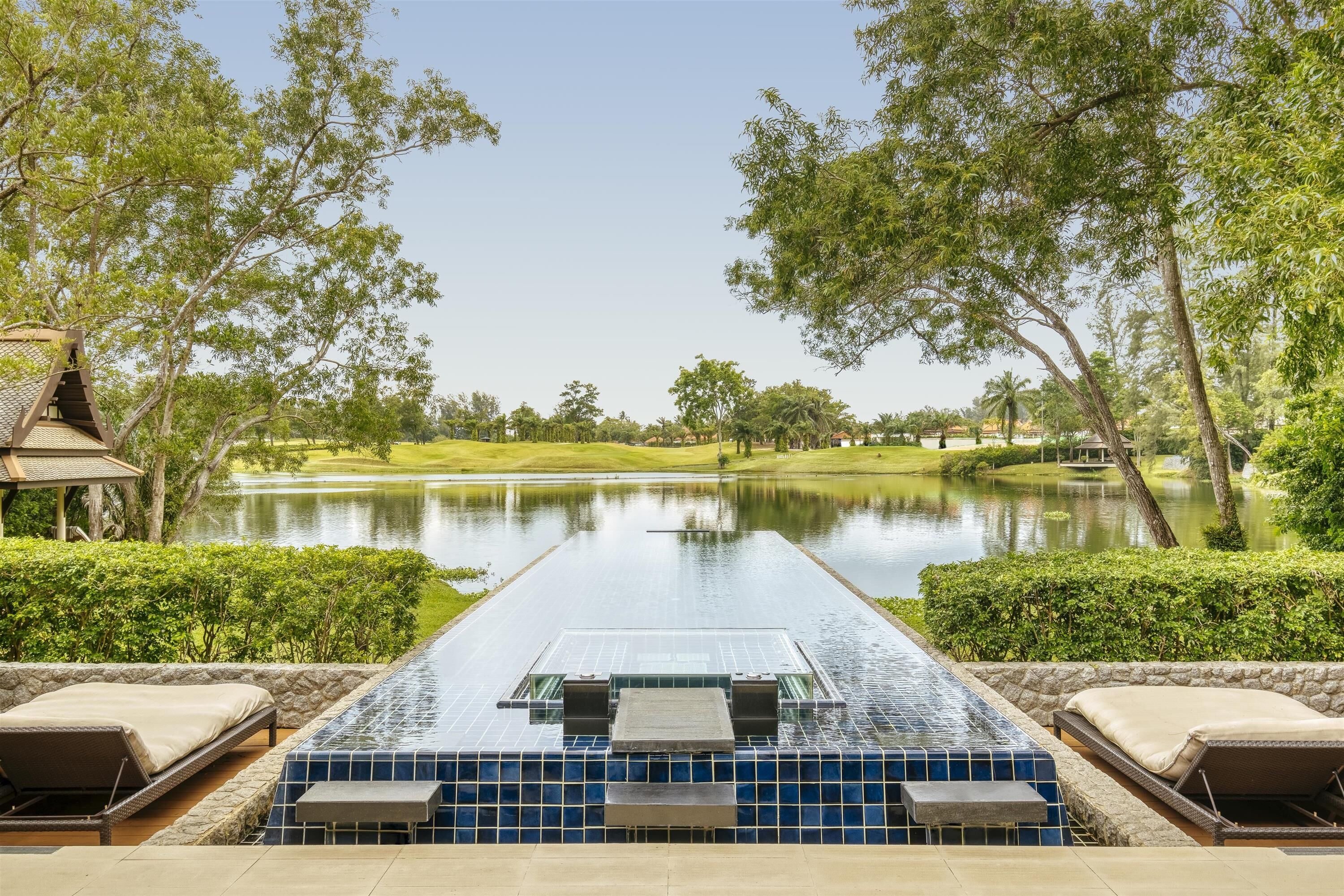 Piscina infinita con vistas despejadas a un lago y un campo de golf.