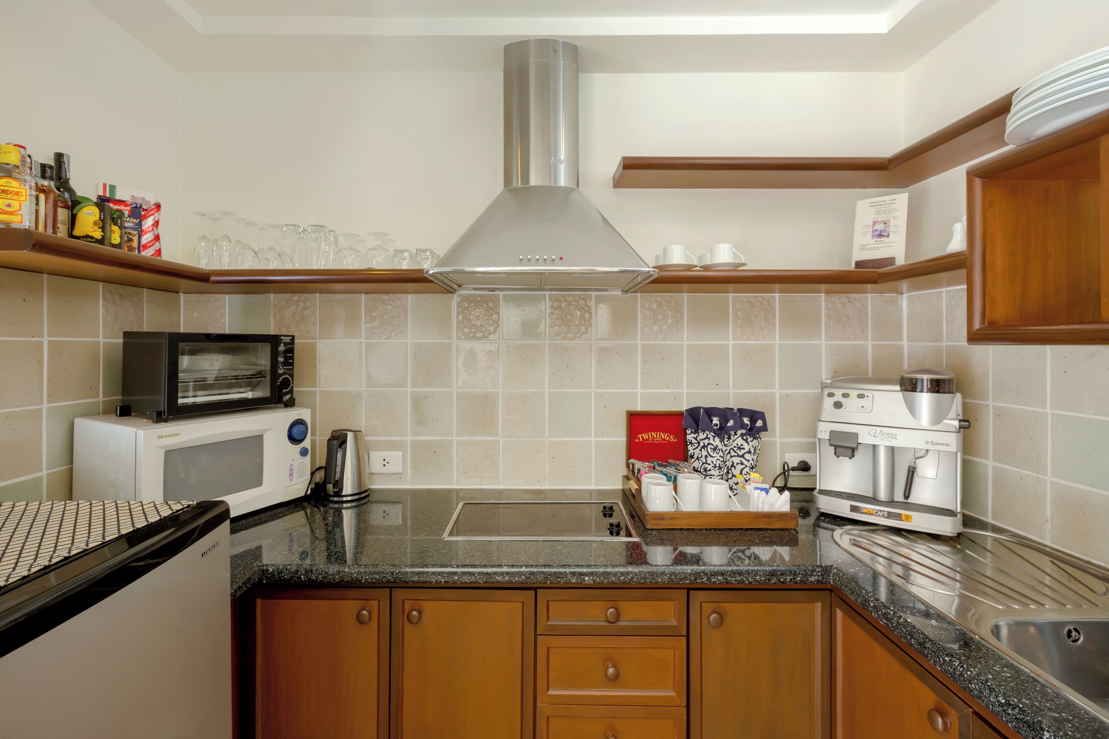 A modern kitchen with a microwave, toaster, coffee maker, and a stainless steel range hood.