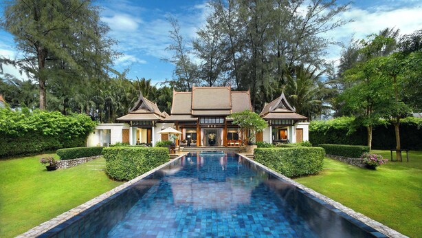 A large house with a swimming pool, surrounded by lush greenery and trees.
