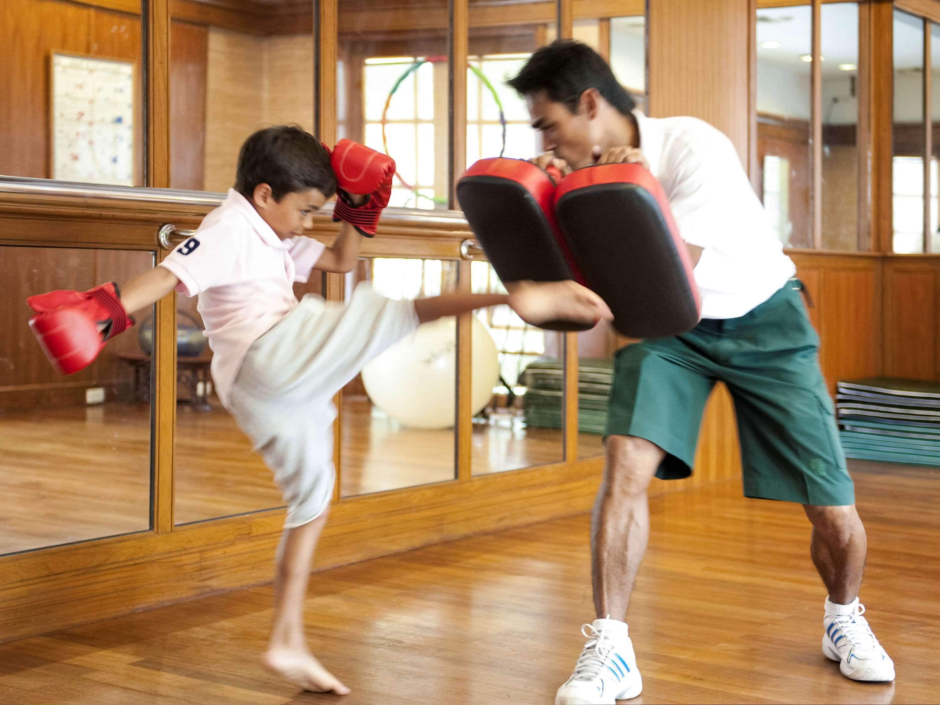 A martial arts training session in a room with wooden floors and mirrored walls.