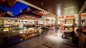 A spacious indoor area with a central water feature, seating areas, and a high ceiling with wooden beams.
