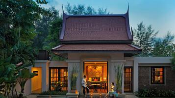 A traditional building with a tiled roof, a pool, and a well-maintained garden.