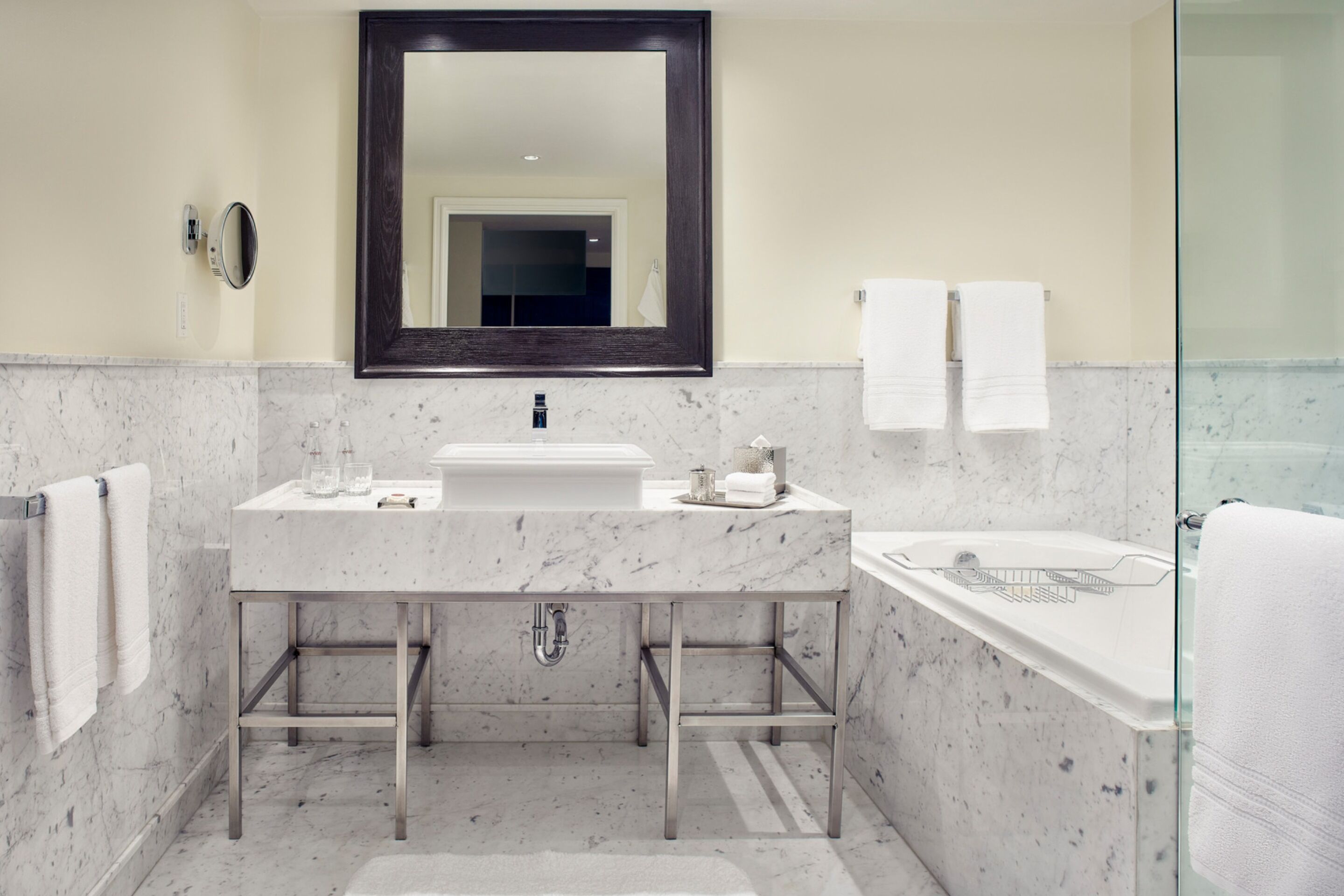 Un baño moderno con un lavamanos de mármol, un espejo grande y una ducha con paredes de vidrio.