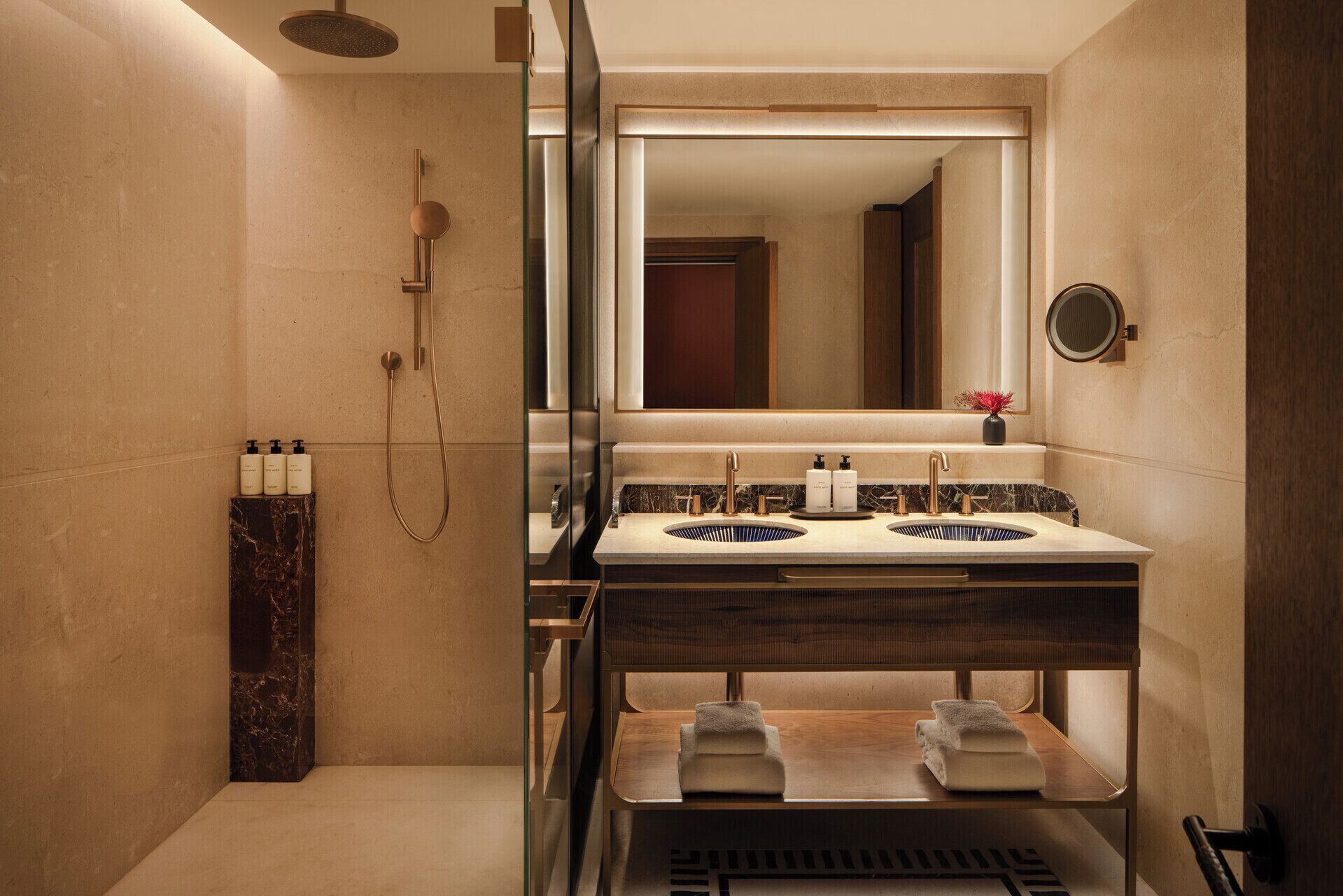 A modern bathroom with a glass-enclosed shower, dual sinks, and a mirror above the vanity.