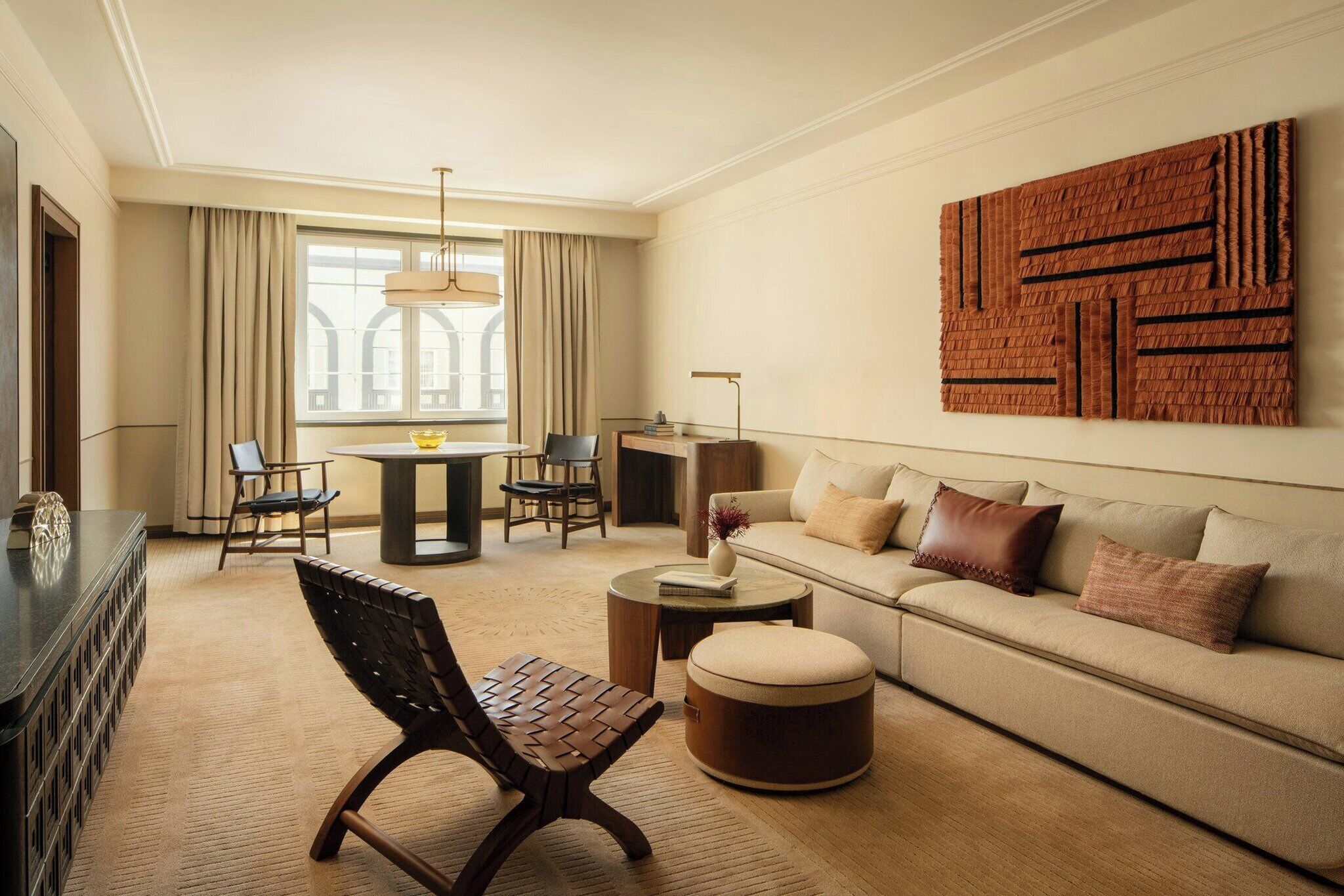 Uma sala de estar moderna com sofá, pufê, cadeiras, mesa de centro e uma área de jantar com mesa e cadeiras.