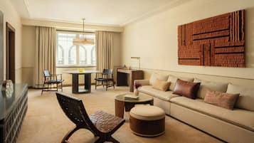 Uma sala de estar moderna com sofá, pufê, cadeiras, mesa de centro e uma área de jantar com mesa e cadeiras.