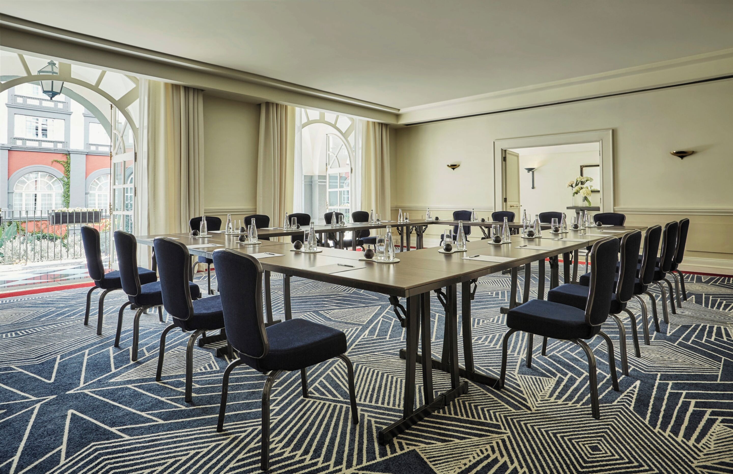Un salón de conferencias con una larga mesa, sillas y piso alfombrado.