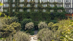 Ein Gebäude mit mehreren Fenstern und Balkonen, umgeben von üppigem Grün und einem Gartenweg.