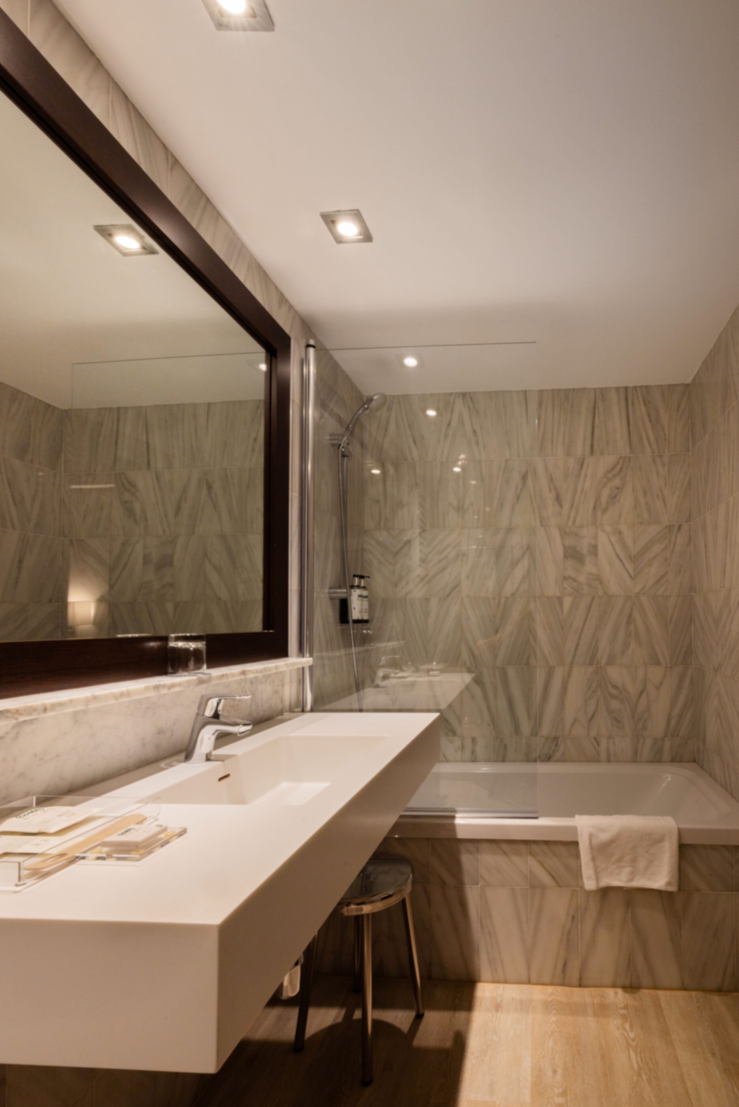 Un baño moderno con un espejo grande, dos lavamanos, una ducha y una bañera.