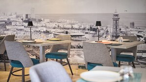 A dining area with a cityscape view, tables with chairs, and two black floor lamps. - Catalonia Atenas (Barcelona)