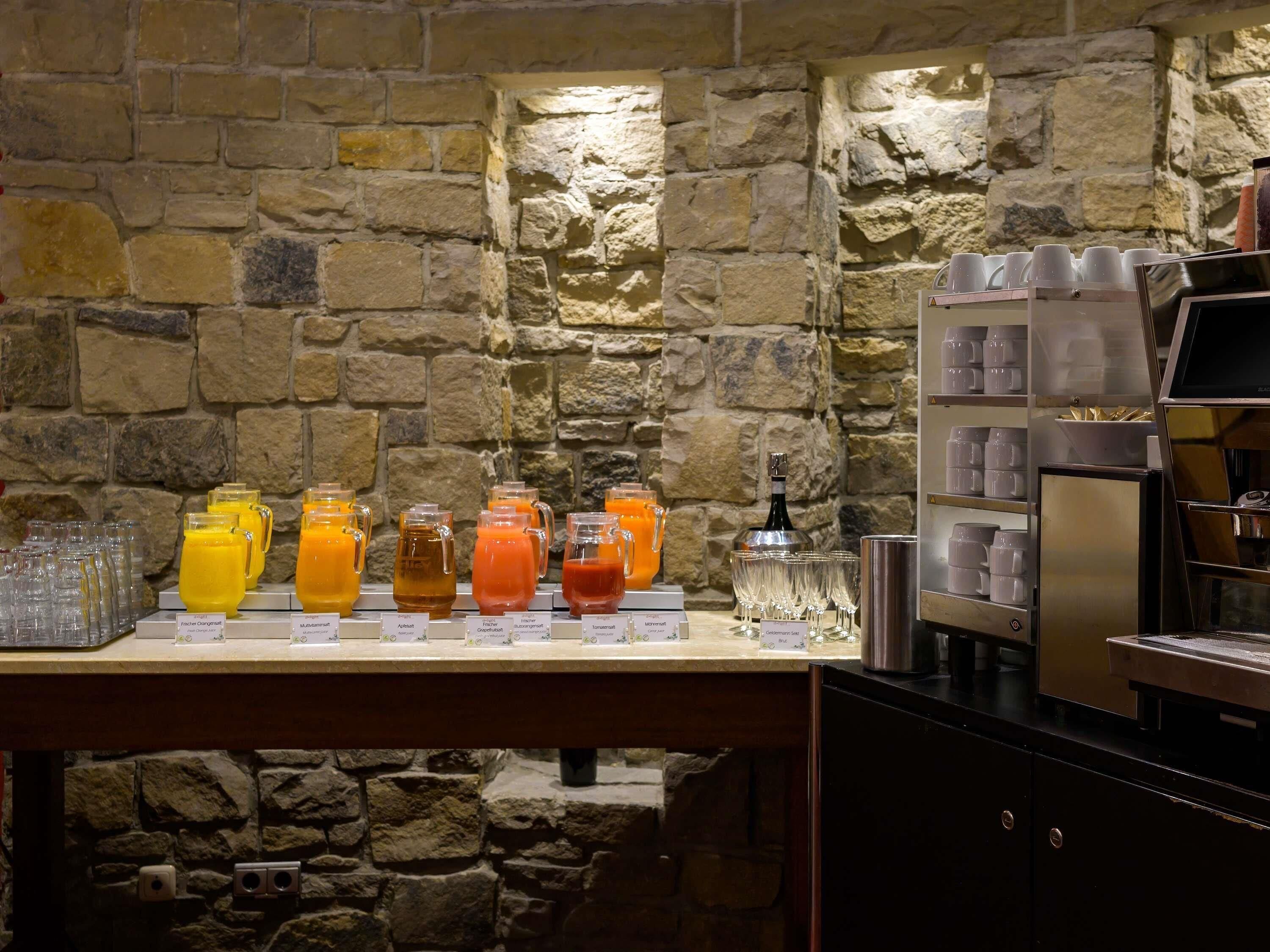 En morgenmadsbuffet med forskellige frugtjuicer og en kaffemaskine.