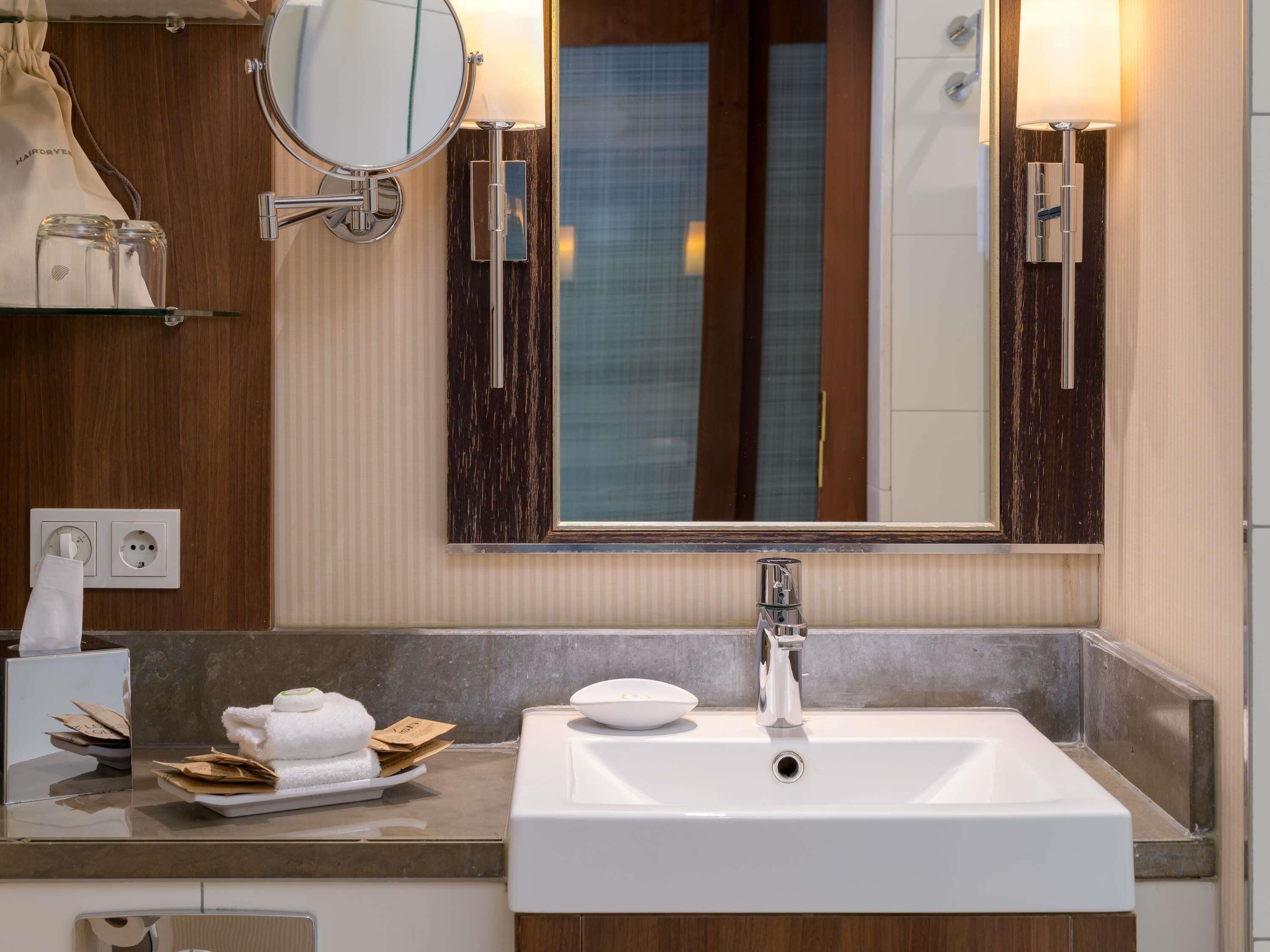 A bathroom with a white sink, a mirror, and two wall-mounted lights.