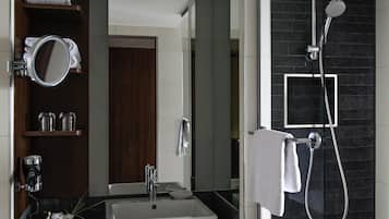 Un baño moderno con un lavamanos rectangular, un cabezal de ducha de mano y un perchero para toallas.