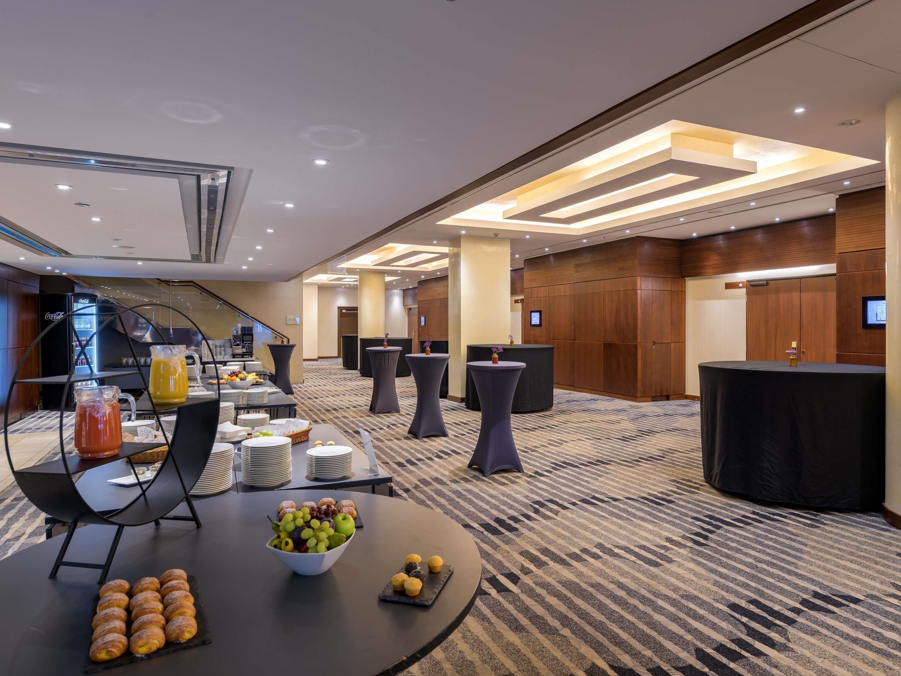 A hotel lobby with a buffet table, round tables, and a reception desk.