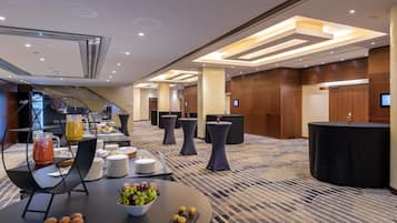 A hotel lobby with a buffet table, round tables, and a reception desk.