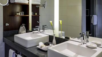A modern bathroom with two large sinks, a mirror, and a vanity area with toiletries.