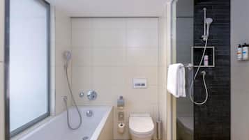Un baño moderno con bañera, inodoro y cabina de ducha con paredes de vidrio.