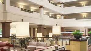 Un vestíbulo de hotel de varios niveles con un área de descanso central, varios pisos y una fuente decorativa.