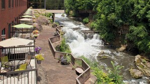 Un paseo ribereño con asientos al aire libre y vistas a una cascada.