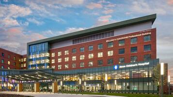 A modern hospital building with a glass facade, a prominent sign for Akron Children's Hospital, and a clear sky in the background.