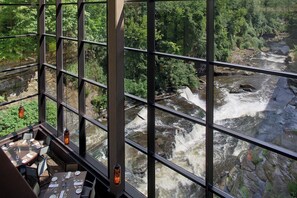 A restaurant with a view of a river and forest through large windows. - Sheraton Suites Akron Cuyahoga Falls (Cuyahoga Falls)
