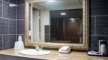A bathroom with a large mirror, a sink, a towel, and a coffee maker.