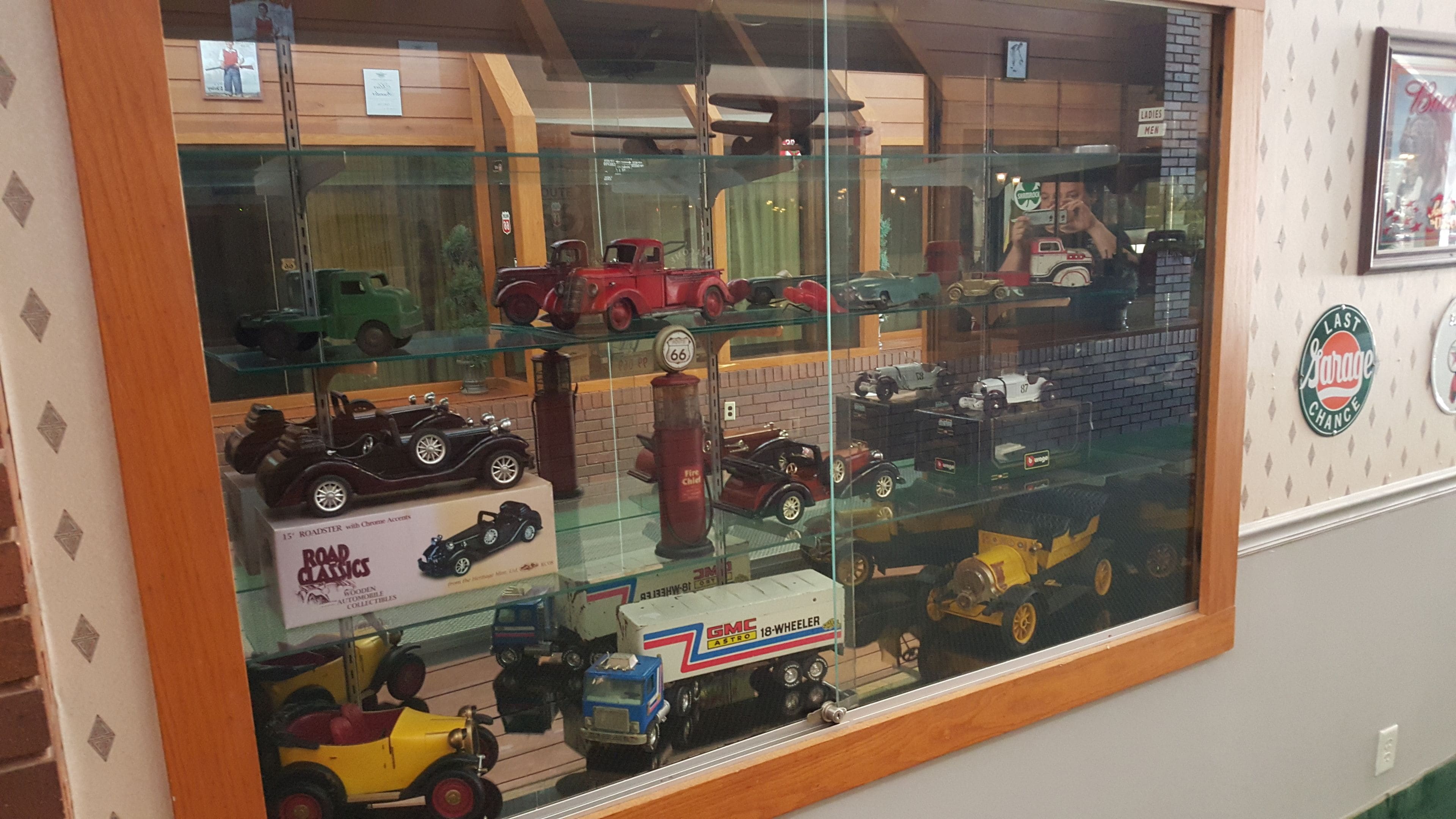 A display case with various model vehicles, including a GMC 18-Wheeler and a vintage car.