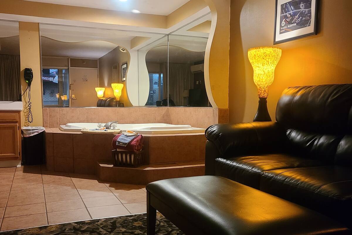 A living room with a sofa, a coffee table, a patterned rug, a lamp, and a large mirror.