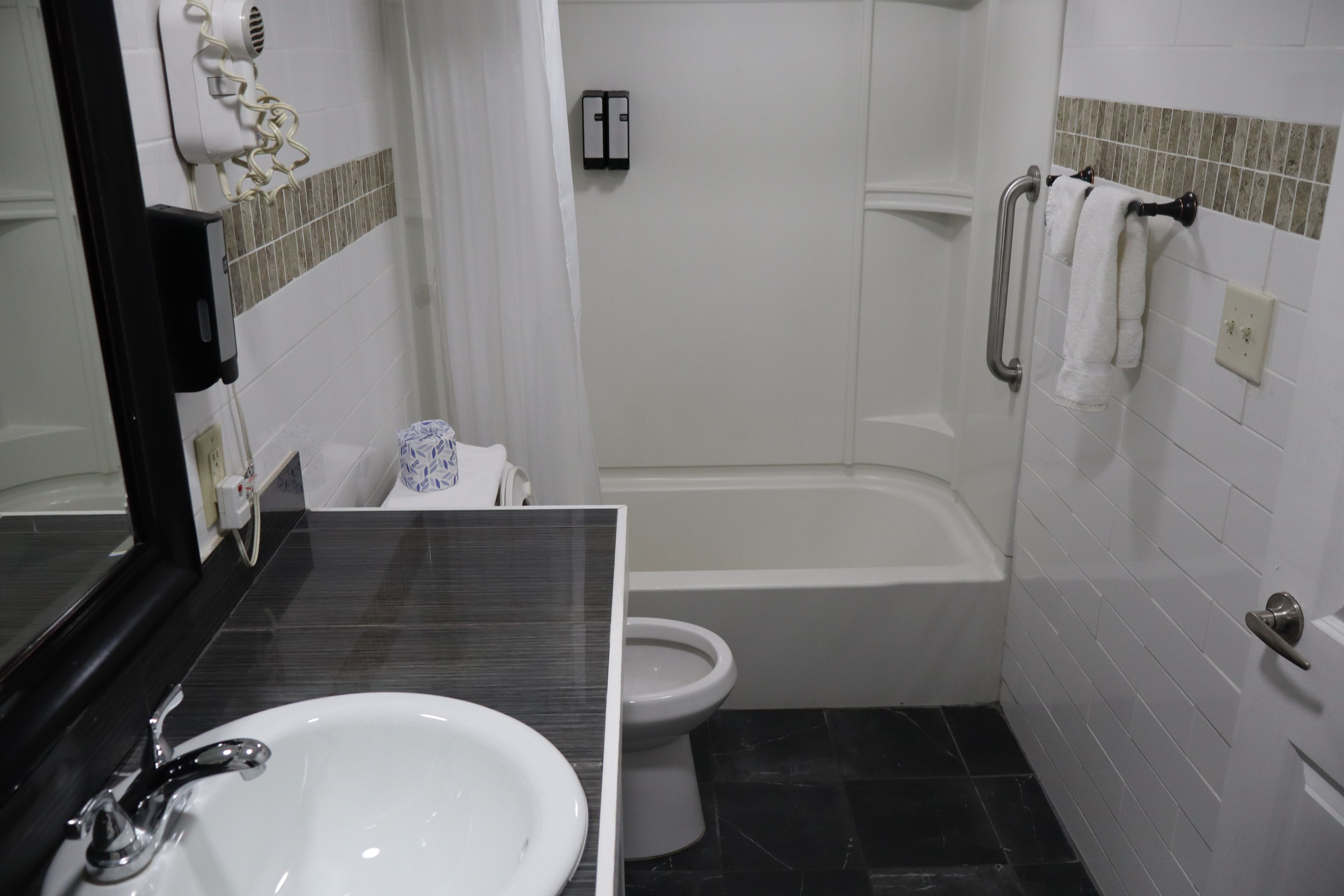 A bathroom with a white sink, toilet, and shower area.
