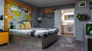 A bedroom with a bed, a dresser, a nightstand, and a wall decorated with license plates. - Route 66 Hotel, Springfield, Illinois (Springfield)