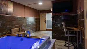 A modern bathroom with a large bathtub, a seating area, and a desk with a chair. - Route 66 Hotel, Springfield, Illinois (Springfield)