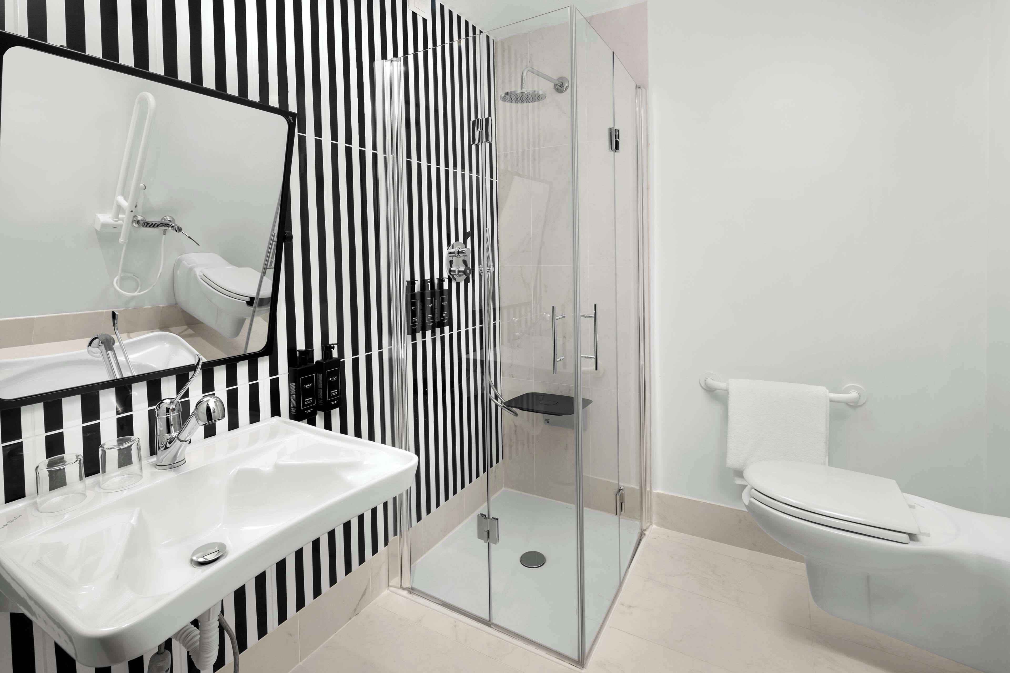 A modern bathroom with a glass-enclosed shower, a white sink, and a toilet.
