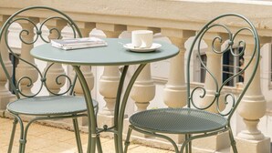 A balcony with a round table and two chairs, overlooking a building with multiple windows and shutters. - Anglo American Hotel Florence, Curio Collection by Hilton (Florence)