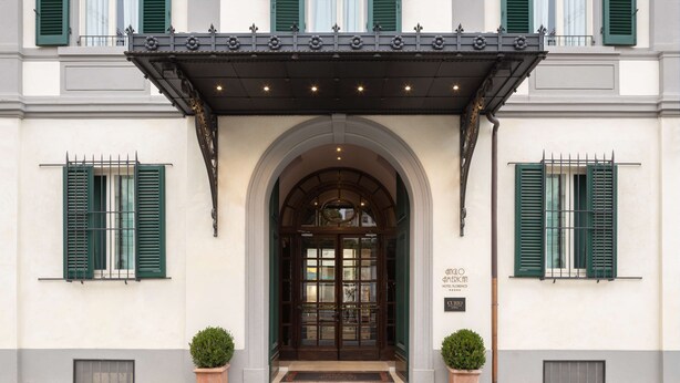 A hotel entrance with a classic arched doorway, green shutters, and a decorative awning. - Anglo American Hotel Florence, Curio Collection by Hilton (Florence)