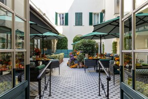 An outdoor seating area with tables and chairs, surrounded by greenery and potted plants. - Anglo American Hotel Florence, Curio Collection by Hilton (Florence)