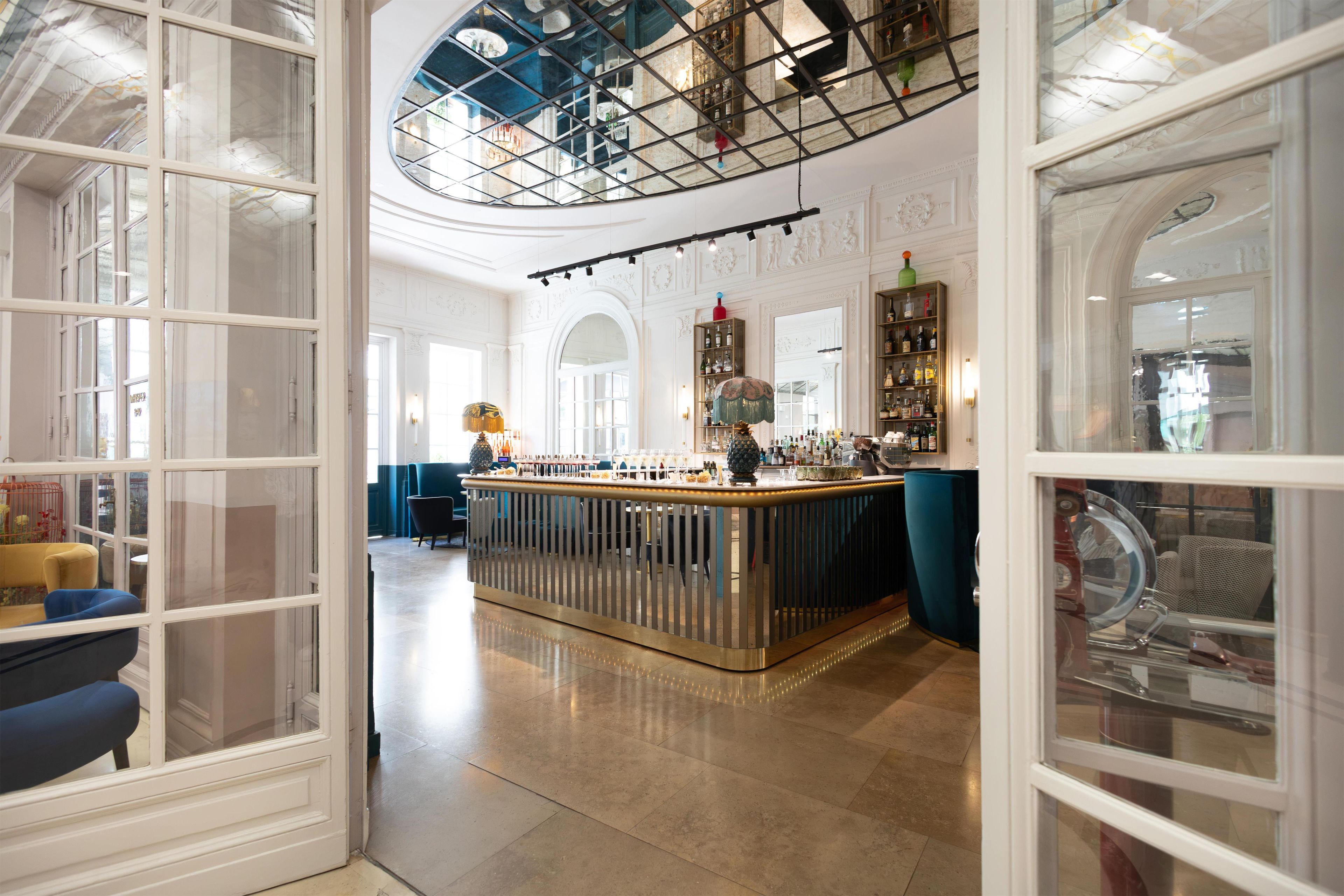 Un vaste espace bar doté d’un haut plafond et d’un comptoir central, entouré de sièges et d’éléments décoratifs.