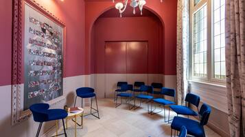 A room with a red and white color scheme, a large mirror with floral decorations, and multiple blue chairs arranged for seating.