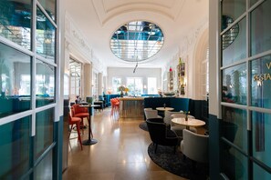 A modern interior with a central bar area, seating arrangements, and large windows allowing natural light. - Anglo American Hotel Florence, Curio Collection by Hilton (Florence)