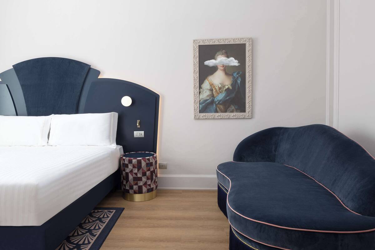 Ein modernes Schlafzimmer mit einem Bett, einem Sessel und einem gerahmten Kunstwerk an der Wand.