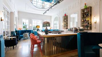 Zona bar con soffitto alto, un bancone centrale e diverse disposizioni di posti a sedere.