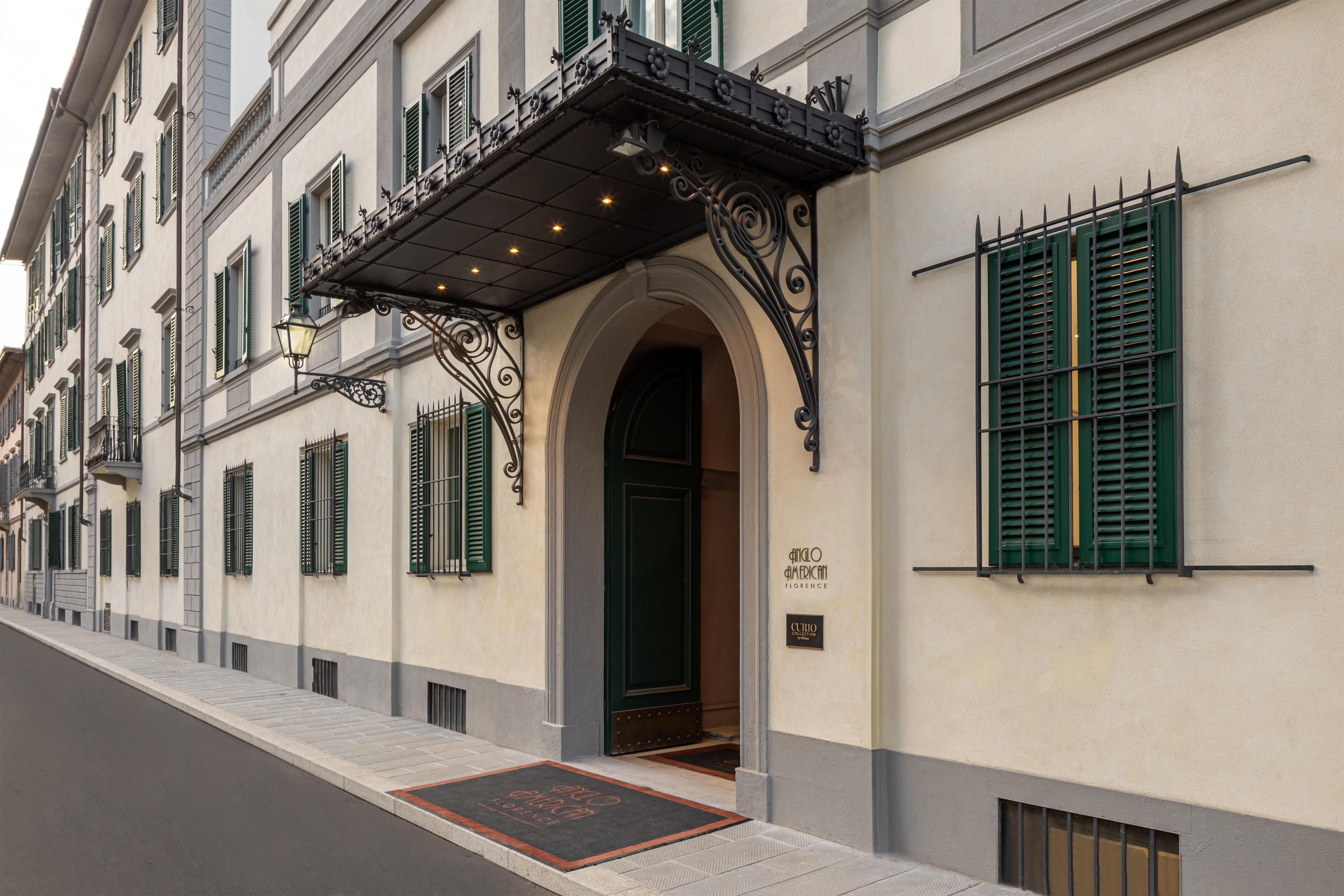 Une façade d’immeuble de style architectural classique, caractérisée par une entrée imposante avec un portail en arc de cercle et des éléments décoratifs en métal.