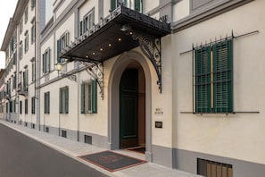 A building facade with a classic architectural style, featuring a prominent entrance with an arched doorway and decorative metalwork. - Anglo American Hotel Florence, Curio Collection by Hilton (Florence)