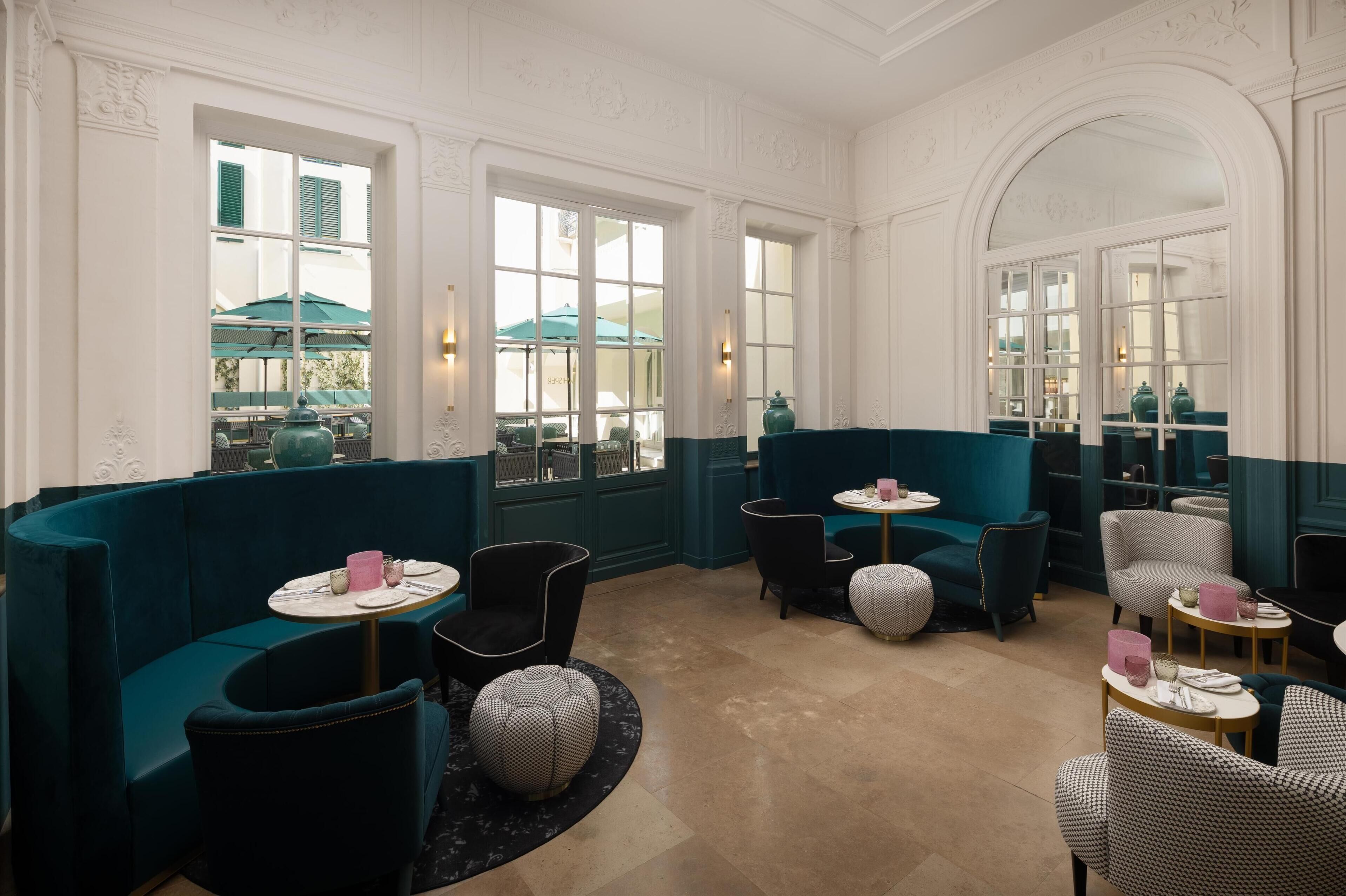 A restaurant with teal-colored booths, round tables, and patterned chairs.