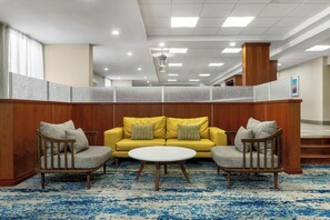 A lobby with a yellow sofa, two armchairs, a round coffee table, and a patterned carpet. - Fairfield Inn & Suites Anaheim North/Buena Park. (Buena Park)