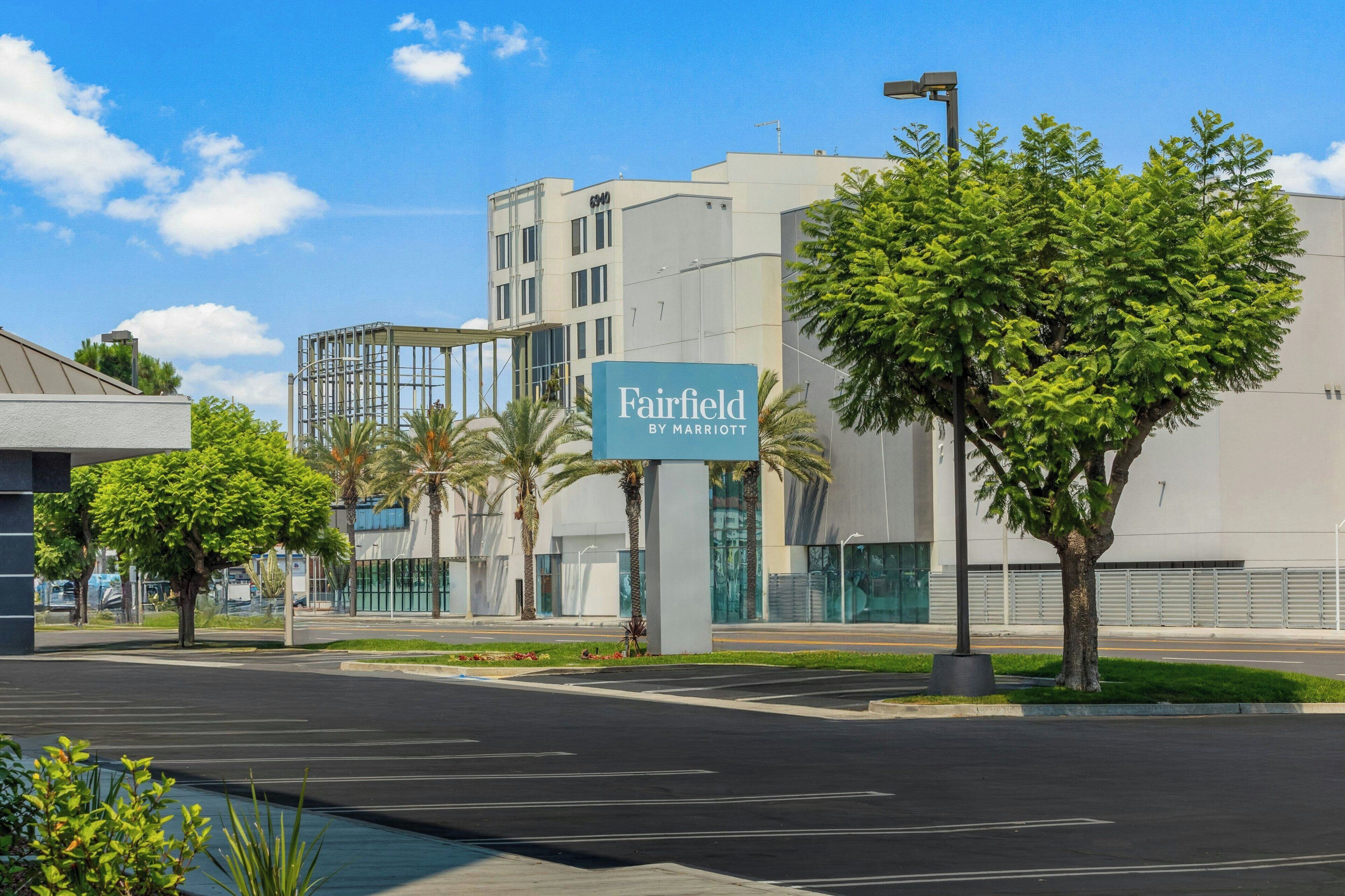 Un hotel Marriott Fairfield con un edificio moderno, estacionamiento y palmeras.