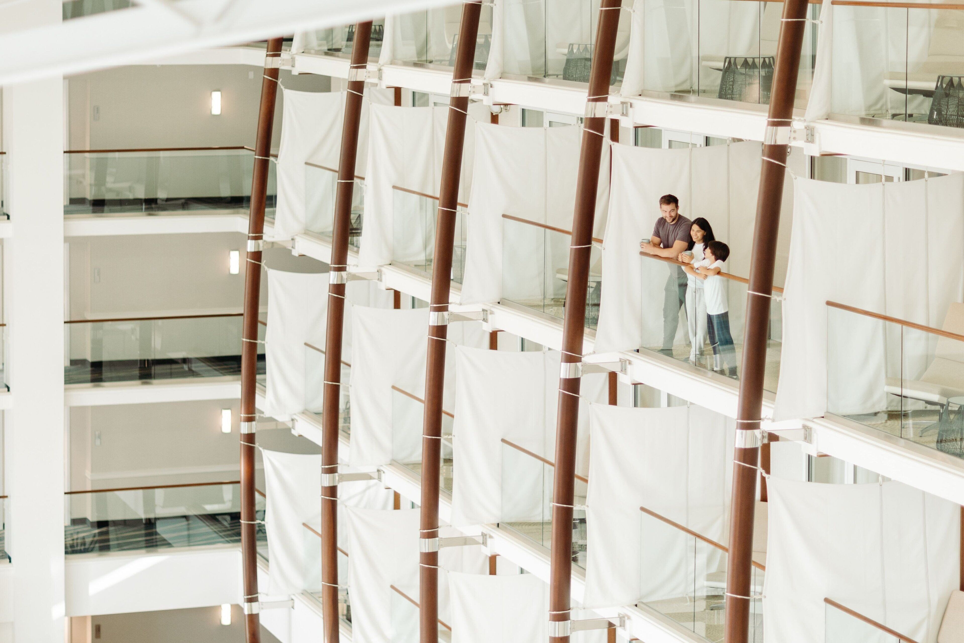 A multi-level atrium with glass railings and white fabric panels.